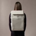 Lieblingstasche Bali Pro light grey vegan leather backpack with flap closure and front pocket, worn by a person.