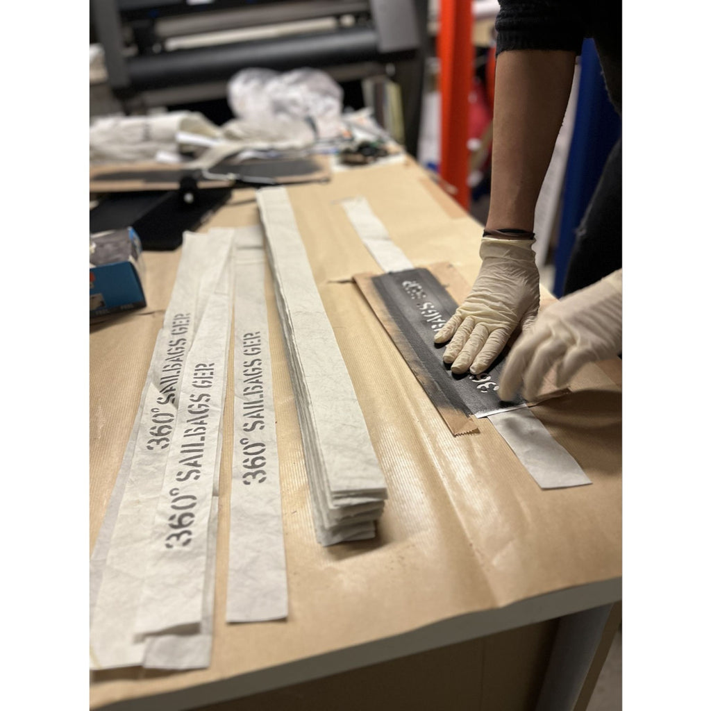 Lieblingstasche Barkasse bag production process with hands in gloves applying stenciled branding to recycled sailcloth