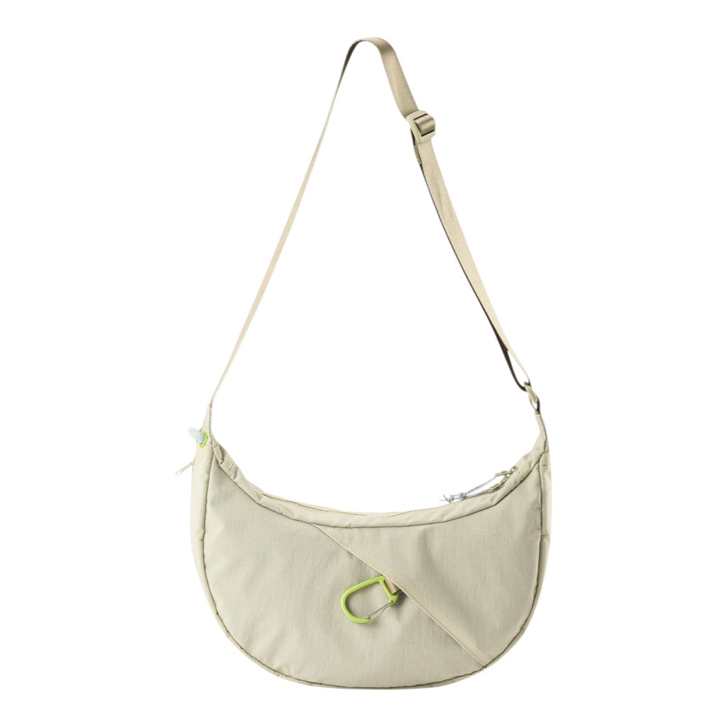 Lieblingstasche beige crescent-shaped sling bag with an adjustable strap and a bright green carabiner detail.