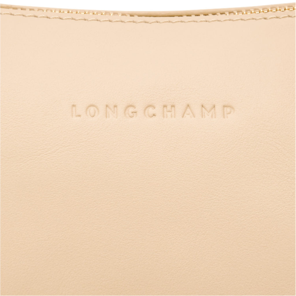 Close-up of a beige leather Lieblingstasche shoulder bag featuring the embossed Longchamp logo and gold zipper detail.