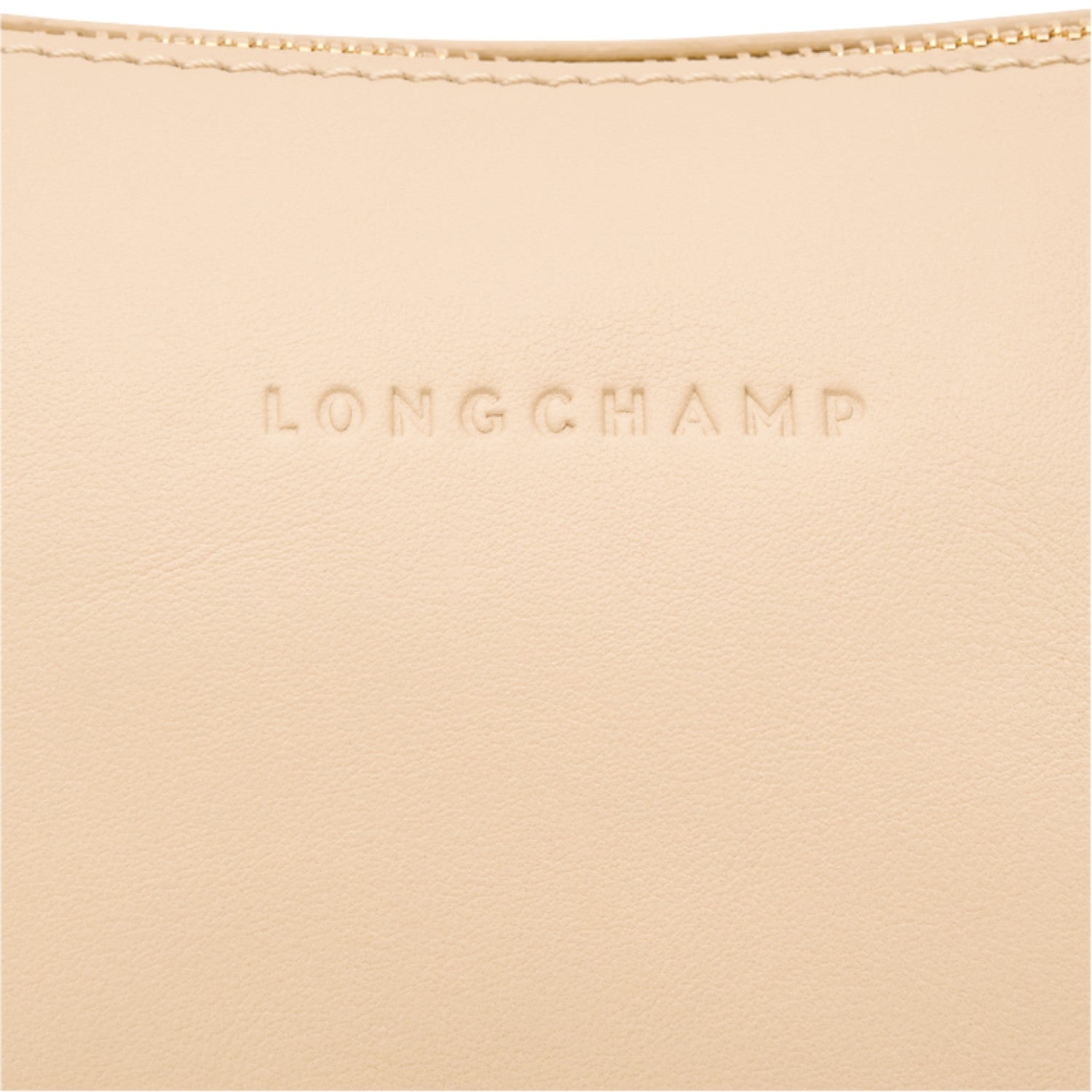 Close-up of a beige leather Lieblingstasche shoulder bag featuring the embossed Longchamp logo and gold zipper detail.