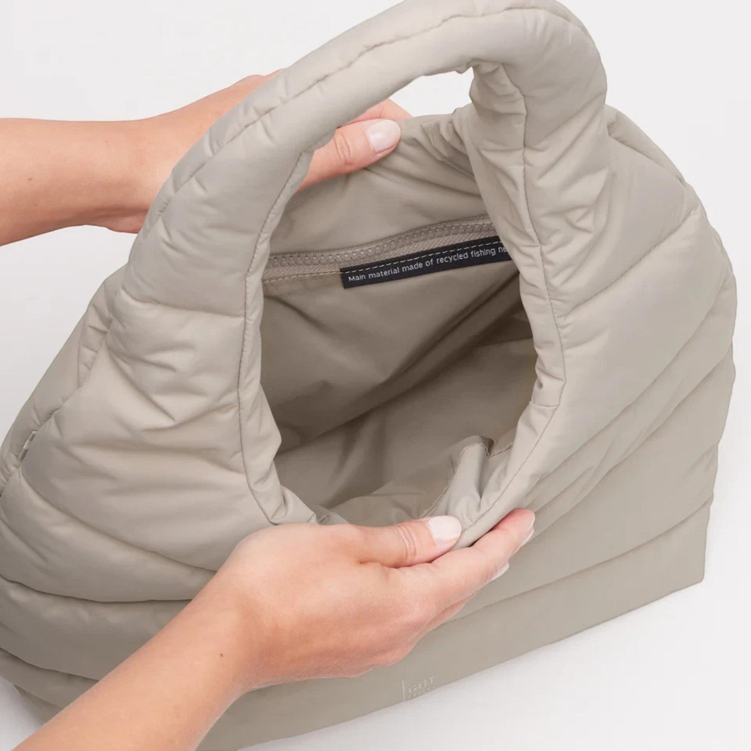 Lieblingstasche beige wavy puffer shoulder bag with recycled material interior label held by hands