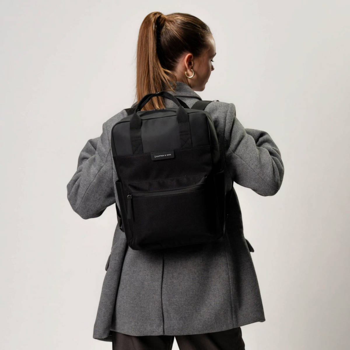 Lieblingstasche Bergen black minimalist backpack with laptop compartment worn by a woman in a grey blazer