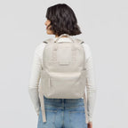 Woman wearing a beige Lieblingstasche Bergen Pro backpack with padded straps and front pocket, back view