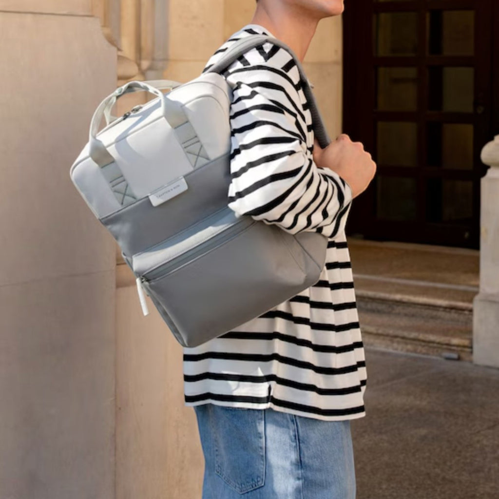 Man wearing a grey and white Lieblingstasche Bergen Pro backpack with padded straps in an urban setting