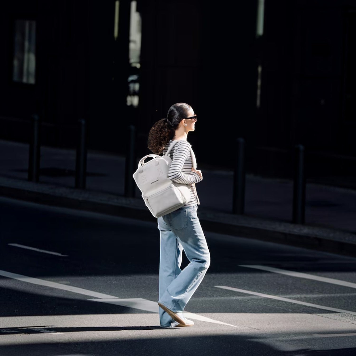 Lieblingstasche Bergen Pro backpack in off-white worn by a woman walking across a city street in casual attire