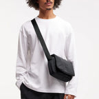 Lieblingstasche Cloud Crossbody Bag in black, made from water-resistant RE:NYNET material, worn by a male model.