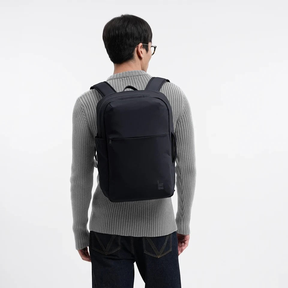 A man wearing a black Lieblingstasche Commuter Pack backpack against a plain white background.