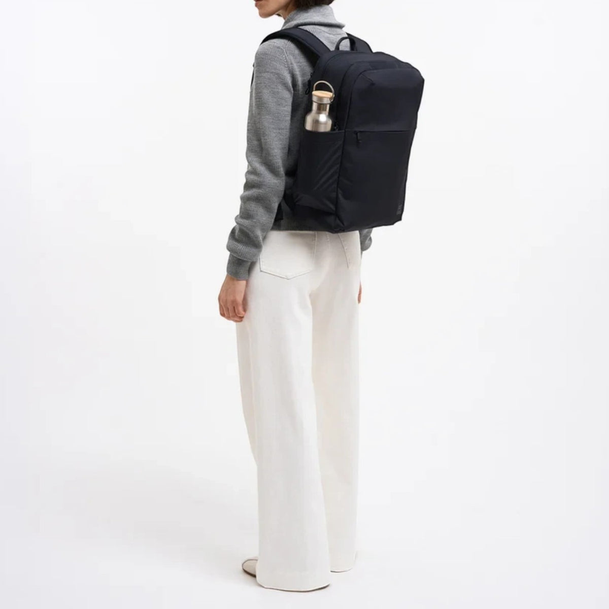 Lieblingstasche Commuter Pack in black worn by a woman with a water bottle in the side pocket