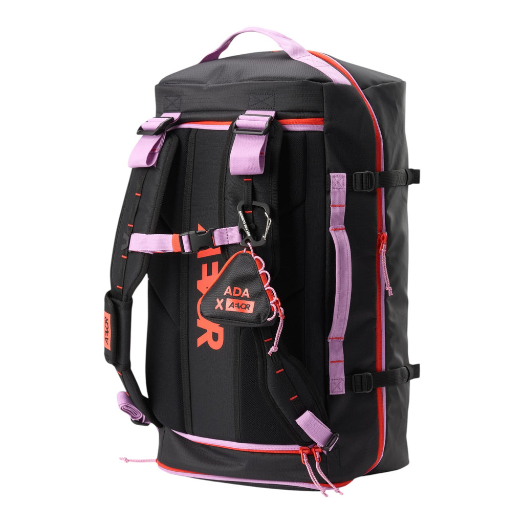 Lieblingstasche black duffel pack with lavender straps and neon orange accents, featuring a triangular accessory pouch.