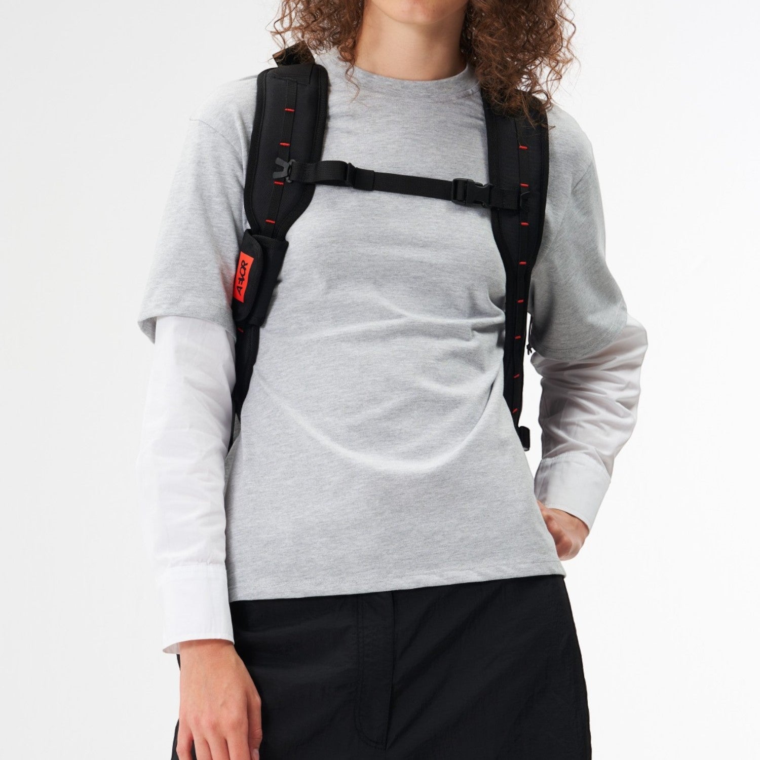 Model wearing a black Lieblingstasche Duffel Pack with red accents on the shoulder straps against a white background