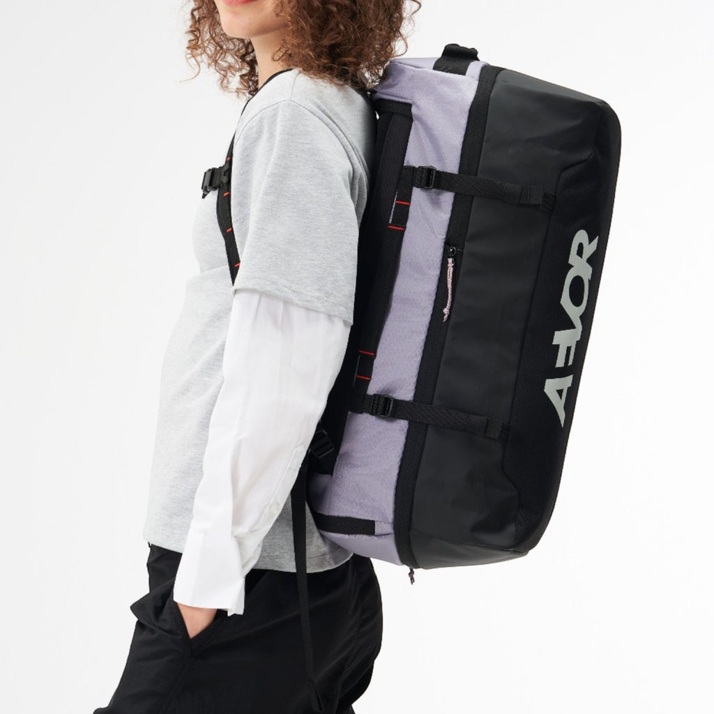 Lieblingstasche Duffel Pack in black and grey worn as a backpack by a woman against a white background