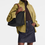 Lieblingstasche black nylon Le Pliage handbag with brown leather straps, worn by a model in a green shirt and denim skirt.