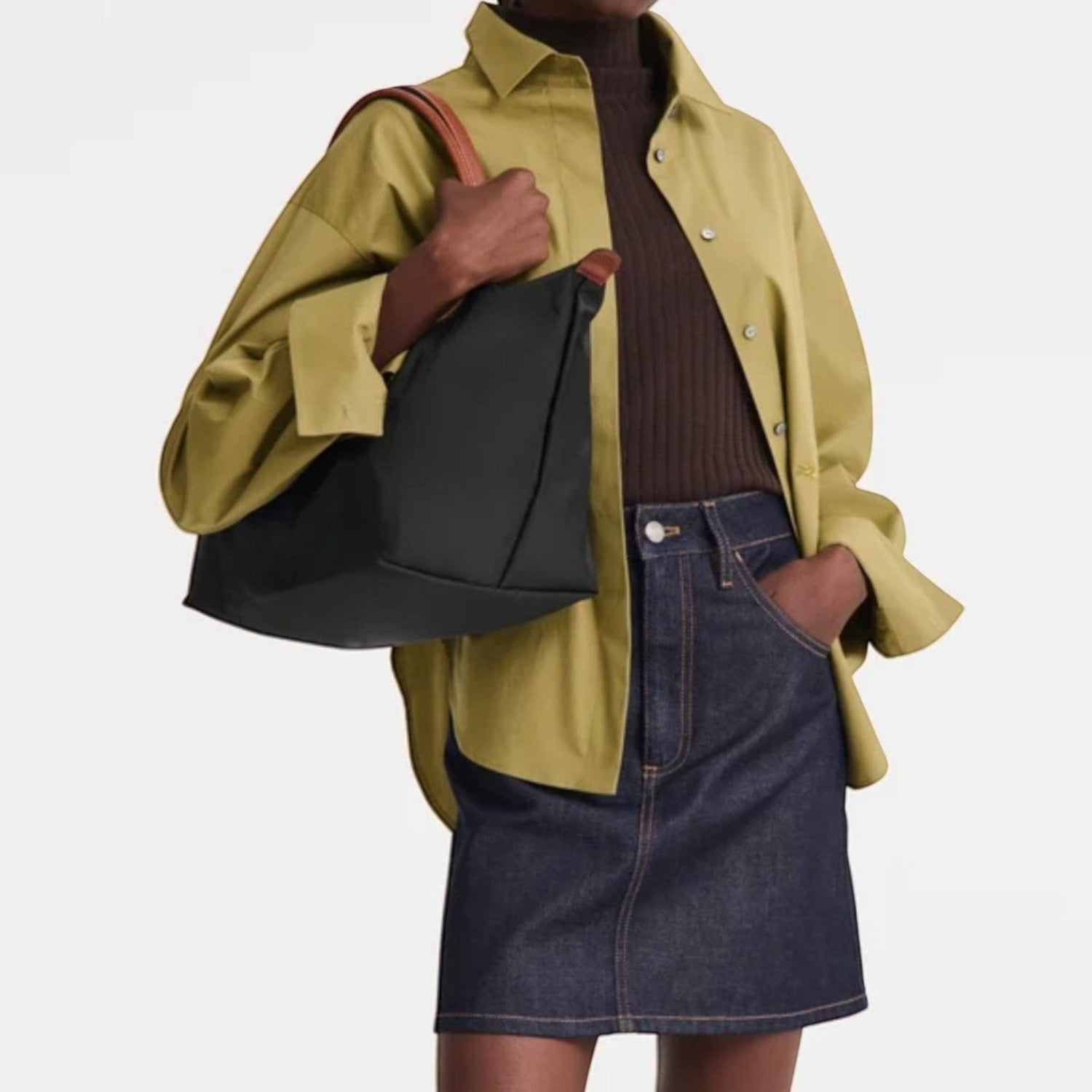 Lieblingstasche black nylon Le Pliage handbag with brown leather straps, worn by a model in a green shirt and denim skirt.