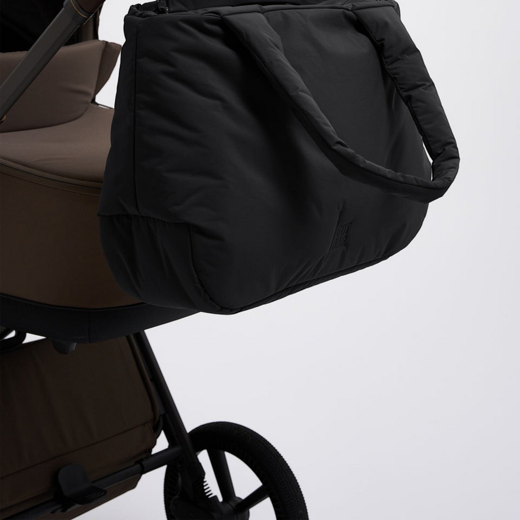 Lieblingstasche Cloud Horizon black padded tote bag hanging from a brown stroller handle