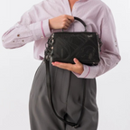 Lieblingstasche black cross-body bag with perforated geometric patterns and a top handle held by a woman