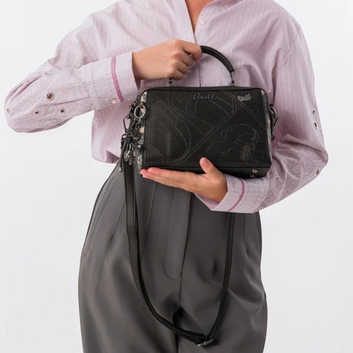 Lieblingstasche black cross-body bag with perforated geometric patterns and a top handle held by a woman