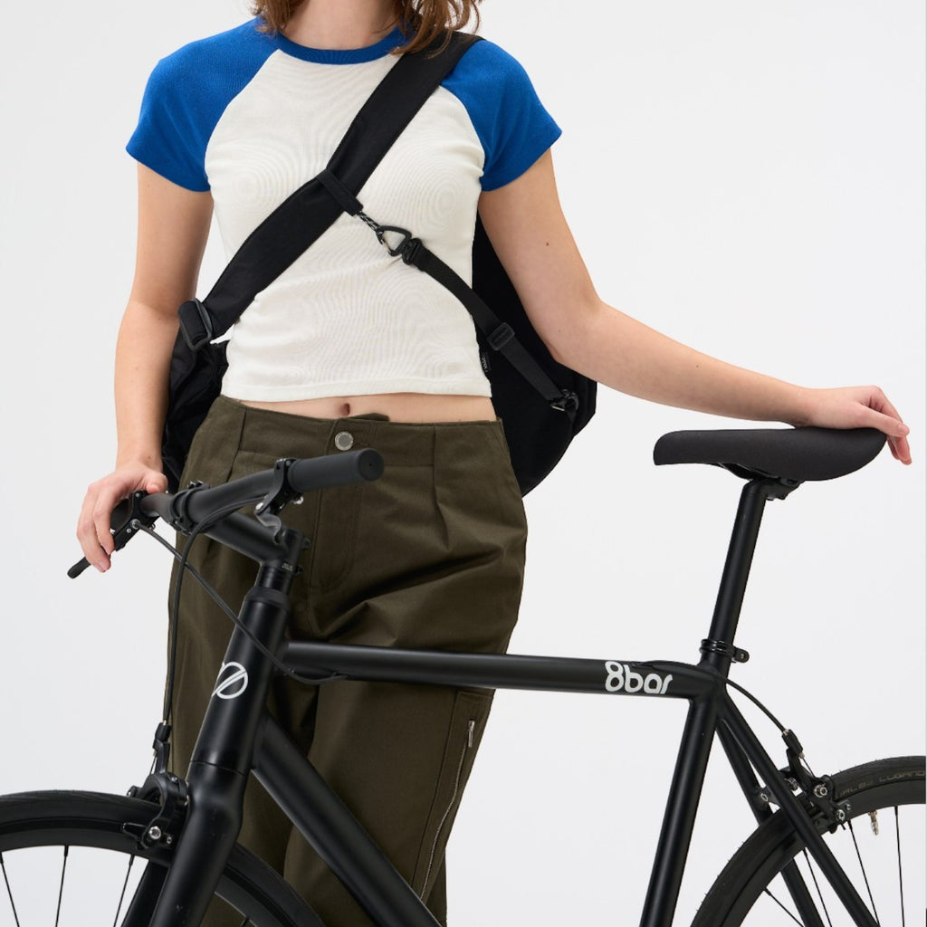 Lieblingstasche black slouchy crossbody bag worn by a woman with a bicycle against a white background