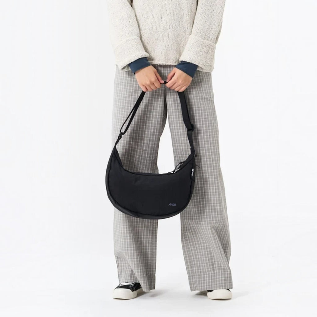Lieblingstasche black water-resistant sling bag worn crossbody by a person in casual clothing