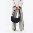Lieblingstasche black water-resistant sling bag worn crossbody by a person in casual clothing