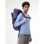 A man wearing a dark blue Lieblingstasche Blok Large backpack with a roll-top design on a white background.