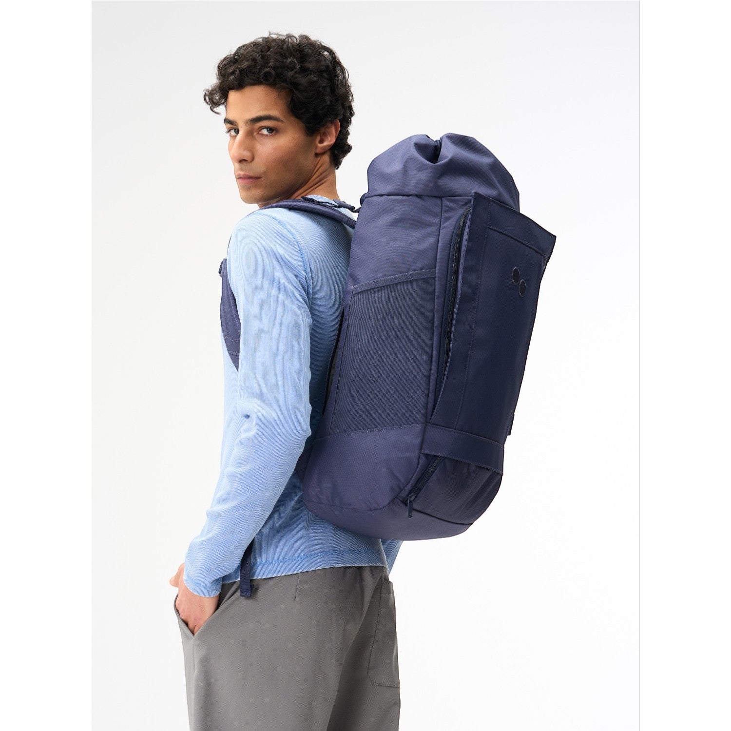 Lieblingstasche Blok Large navy blue cylindrical backpack worn by a man in a light blue long-sleeve shirt