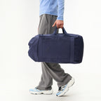 Lieblingstasche Blok Large navy blue duffel bag held by a person wearing grey trousers and light blue top