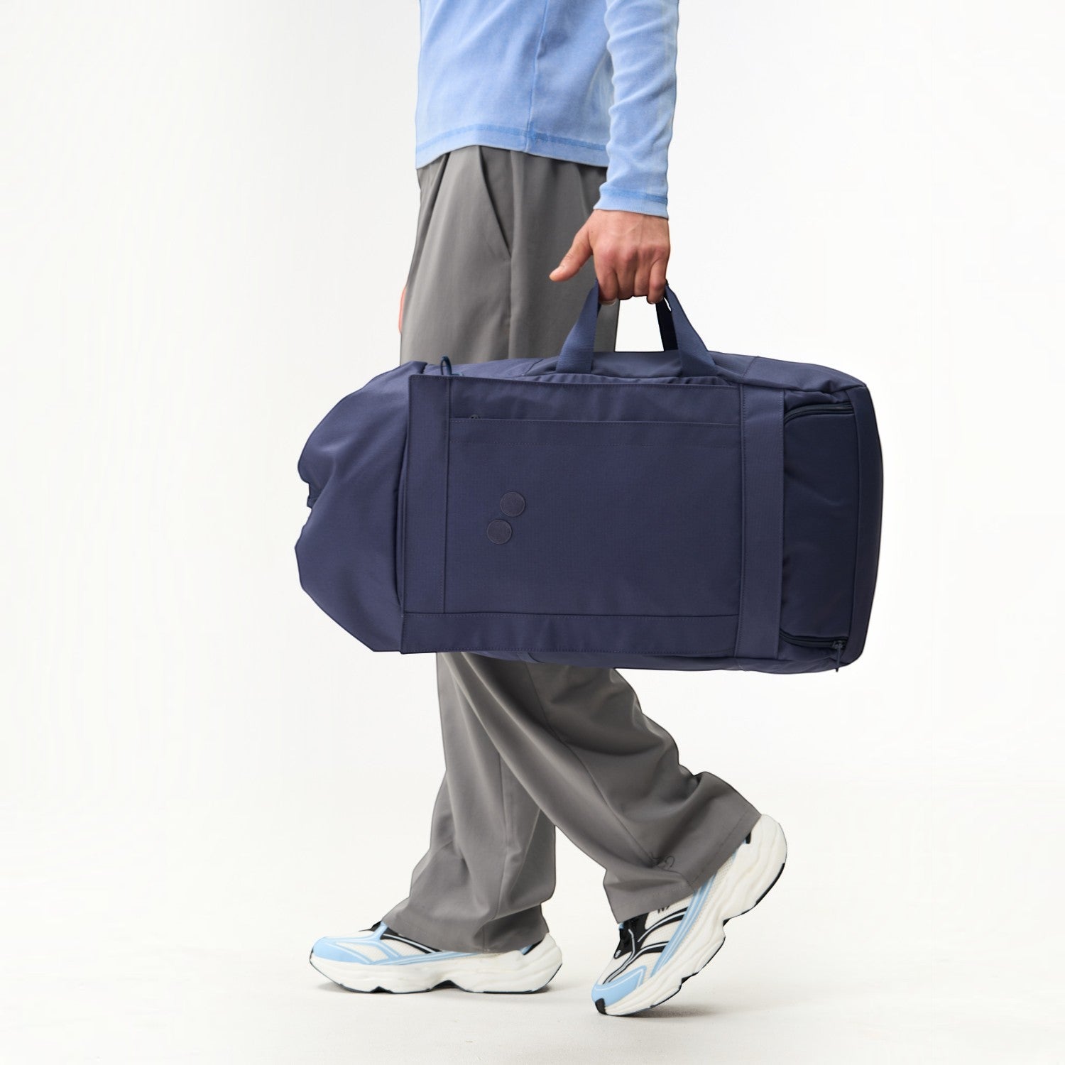 Lieblingstasche Blok Large navy blue duffel bag held by a person wearing grey trousers and light blue top