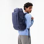 Lieblingstasche Blok Medium backpack in dark blue worn on the back by a man in a light blue long-sleeve shirt