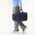 Lieblingstasche Blok Medium navy blue duffel bag carried by a person wearing grey trousers and light blue top