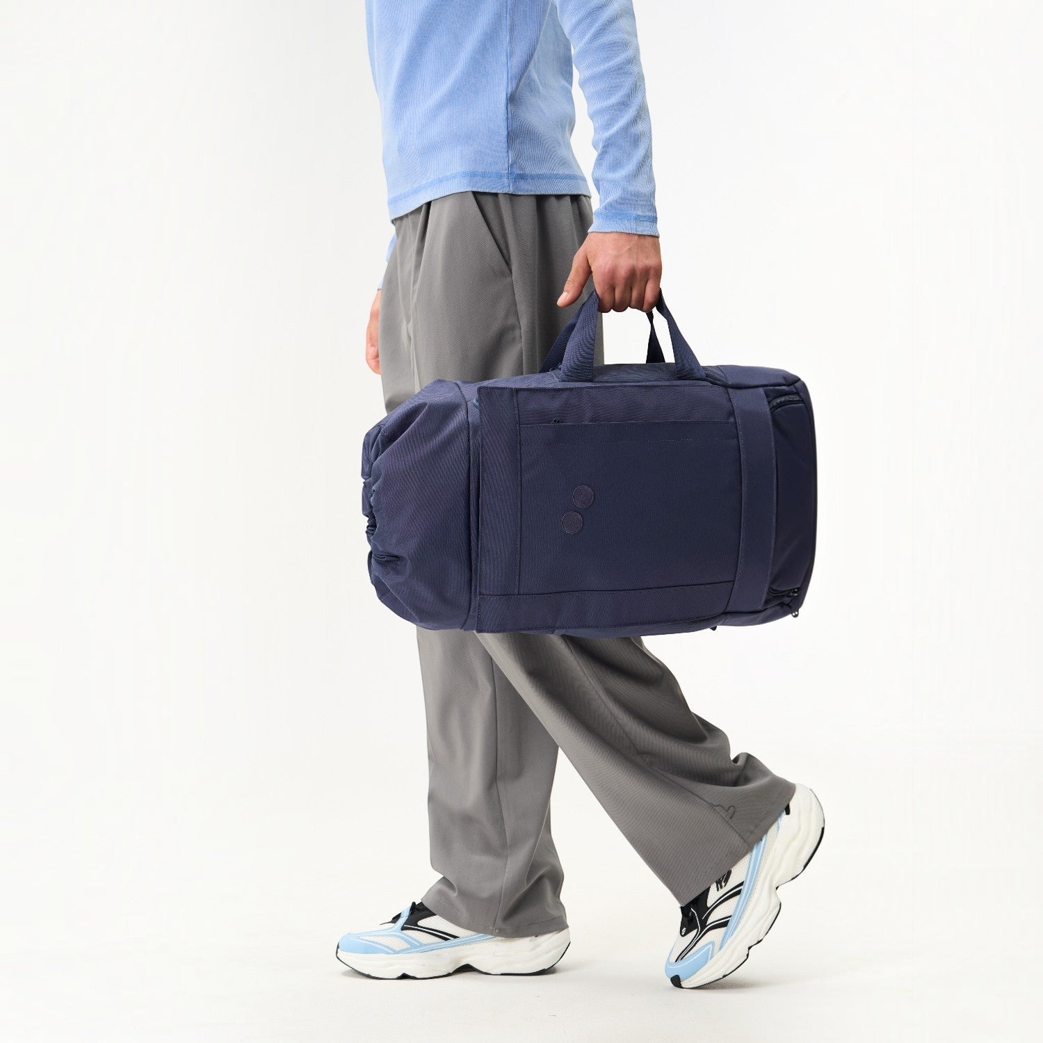 Lieblingstasche Blok Medium navy blue duffel bag carried by a person wearing grey trousers and light blue top