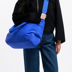 Model wearing a bright blue Lieblingstasche Cloud Horizon tote bag with an adjustable crossbody strap