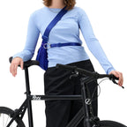 Woman wearing a bright blue Lieblingstasche sling bag across her chest while leaning on a black bicycle