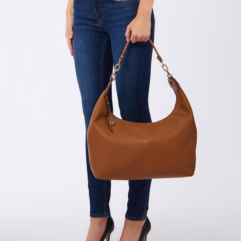 Lieblingstasche ECS Hobo M brown leather shoulder bag with gold chain strap held by a woman in jeans
