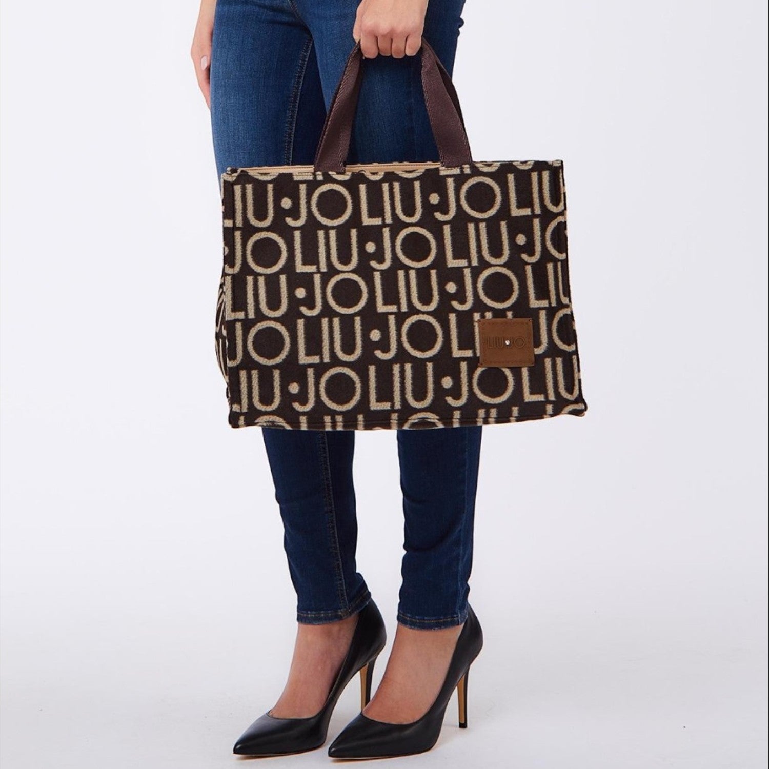 Lieblingstasche brown and beige allover logo print tote bag held by a woman in blue jeans and black heels