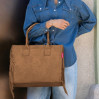 Lieblingstasche Daily Shopper in brown suede with side fringe detail carried by a woman in a denim shirt