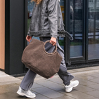 Lieblingstasche Loopbag Hobo in brown teddy fleece with a circular wooden handle carried by a woman in grey outfit