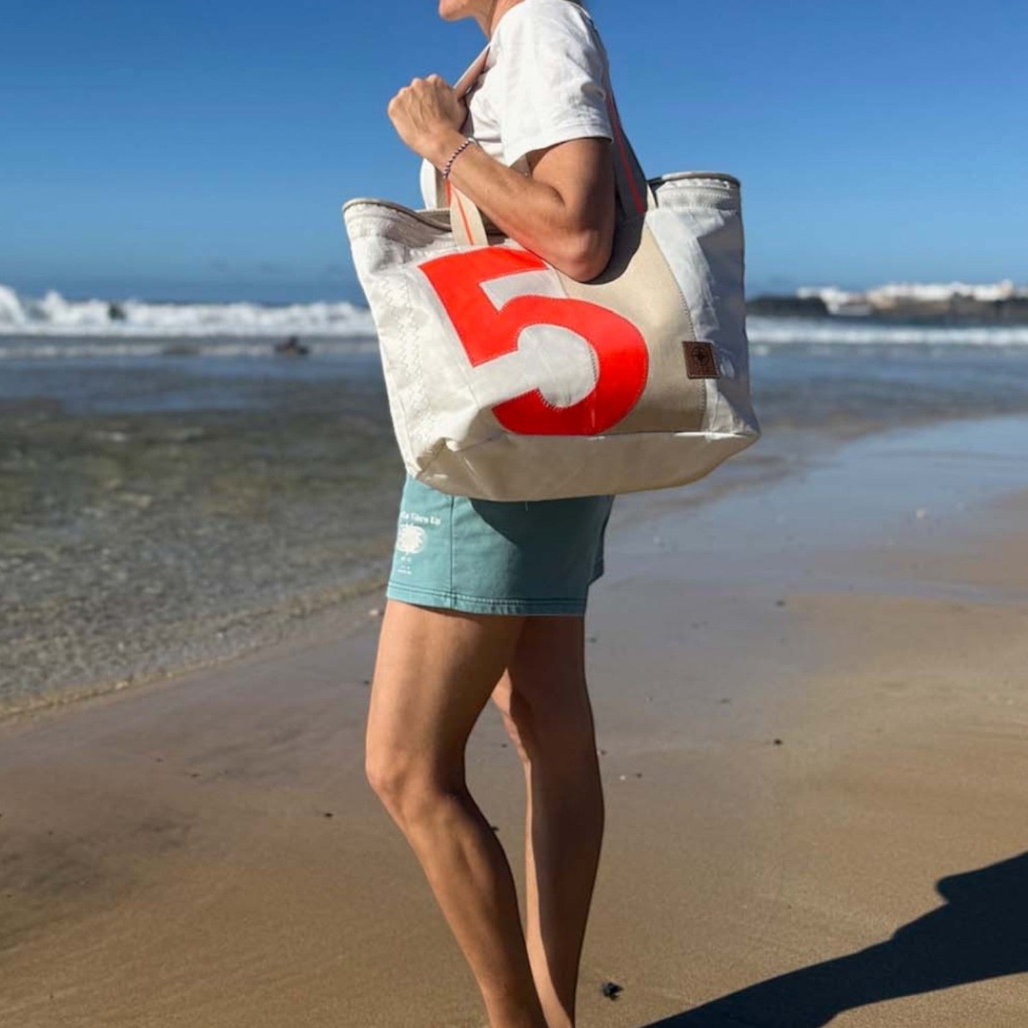 Lieblingstasche large canvas tote bag with a large red number 5 graphic, worn by a woman on a beach.