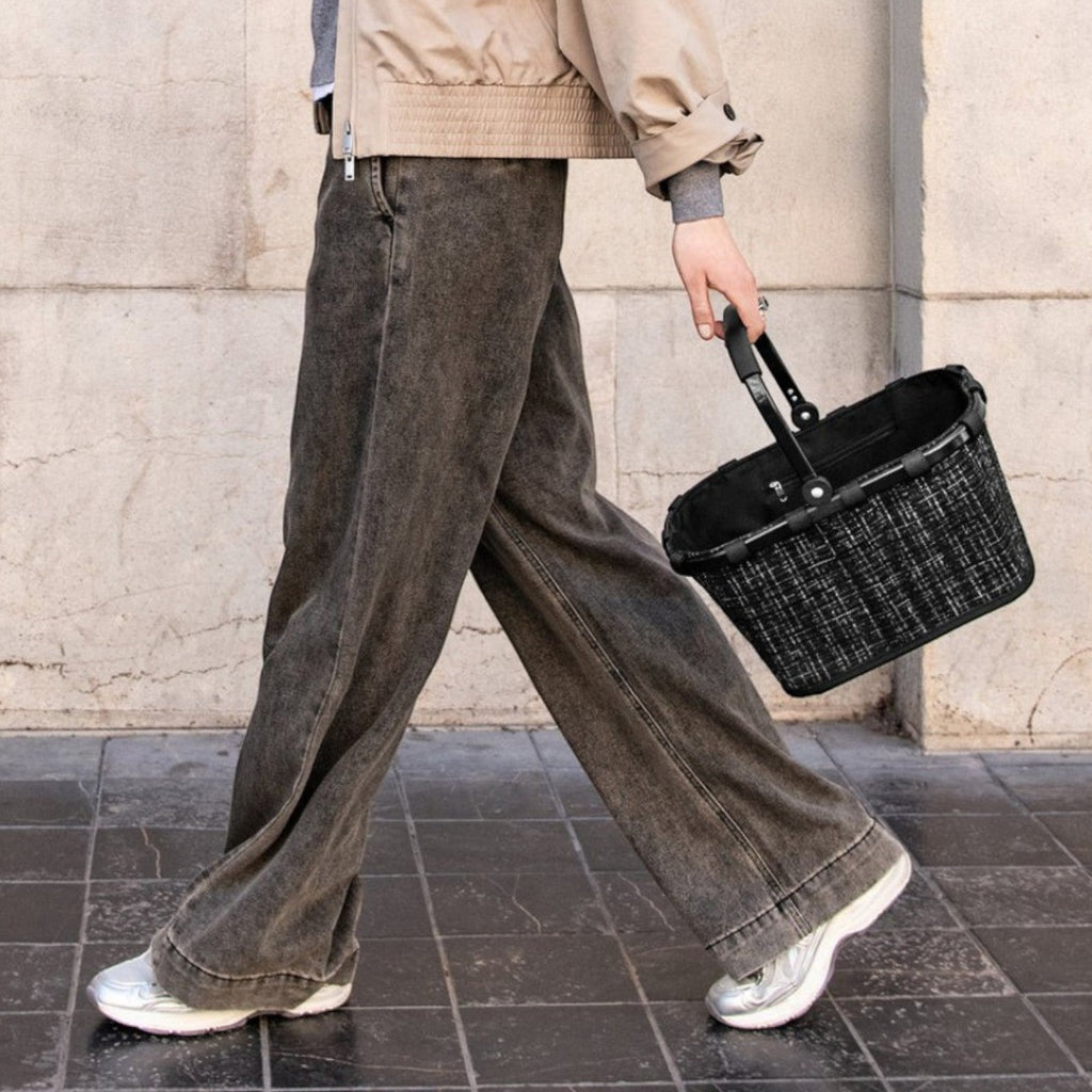 Lieblingstasche Carrybag XS black woven basket with handle, carried by a woman walking outdoors.