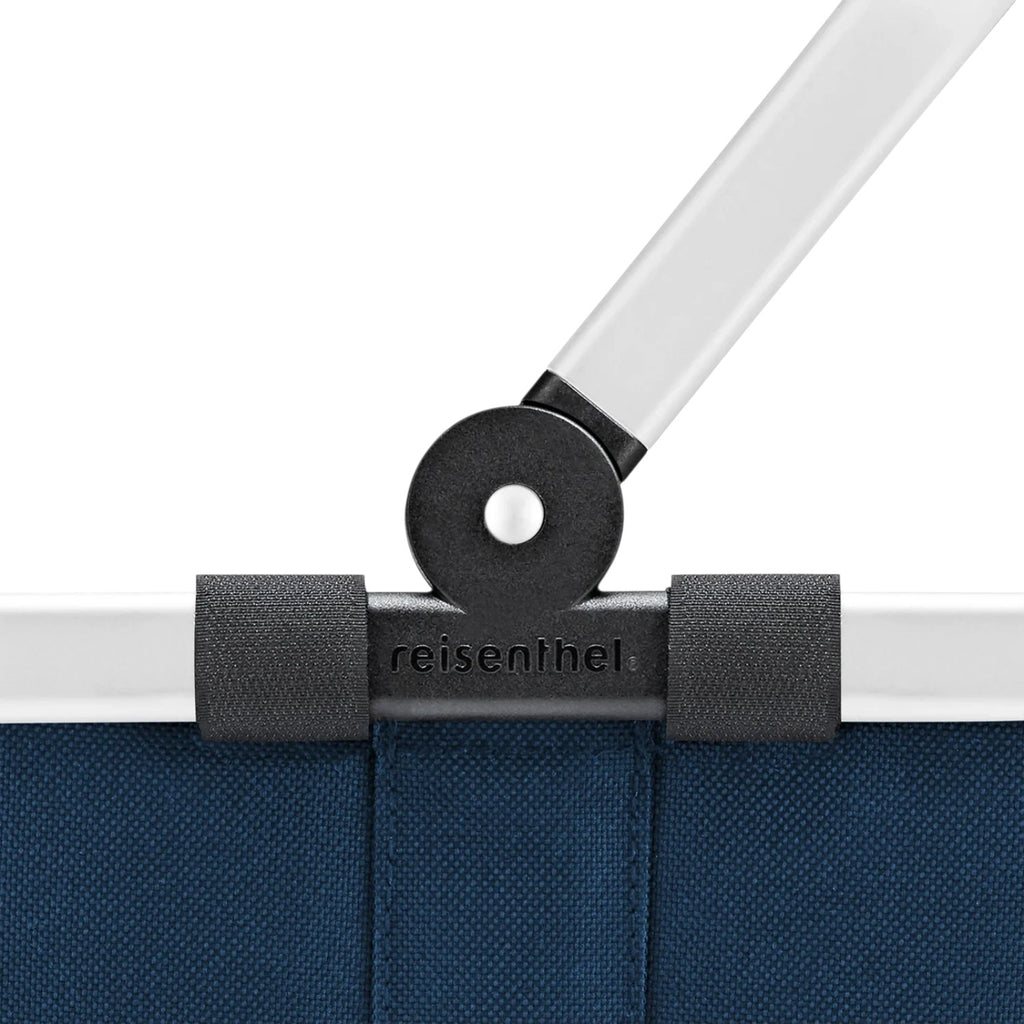 Close-up of the Lieblingstasche Carrybag XS showing the blue fabric, white handle, and black hinge mechanism.