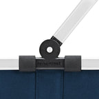 Close-up of the Lieblingstasche Carrybag XS showing the blue fabric, white handle, and black hinge mechanism.