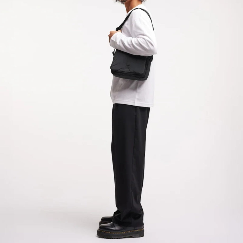 Lieblingstasche Cloud Crossbody Bag in black, worn by a man in a white long-sleeve shirt against a white background.
