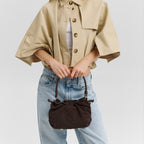 Lieblingstasche Cool Companion Suede S dark brown suede handbag with drawstring closure held by a model