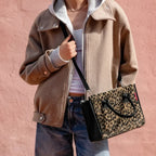 Lieblingstasche Daily Shopper XS in leopard print with black trim, worn as a crossbody bag by a woman in a beige jacket