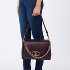 Lieblingstasche Crossbody L handbag in dark brown leather with gold chain detail held by a woman in jeans
