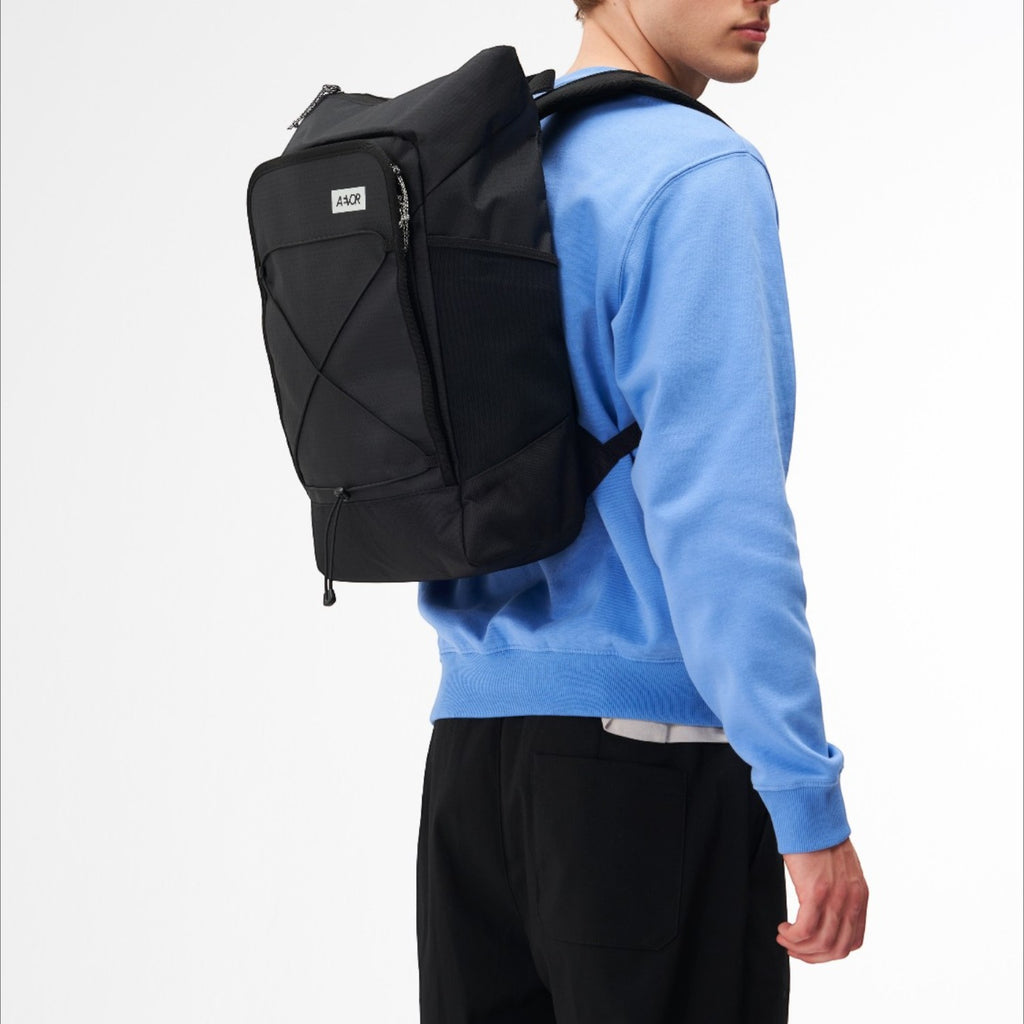 Lieblingstasche Day Pack FLX in black worn by a man, featuring a modern design with side mesh pockets and straps.