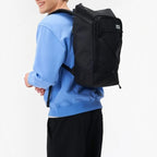 Lieblingstasche Day Pack FLX black backpack worn by a smiling man in a blue sweatshirt against a white background