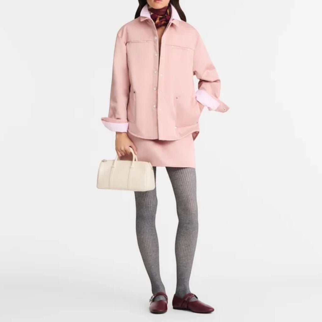 Model wearing a pink jacket and skirt holding a Lieblingstasche Daylong Handtasche M in cream leather