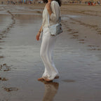 Woman wearing a Lieblingstasche Deern Lütt crossbody bag on a sandy beach at sunset