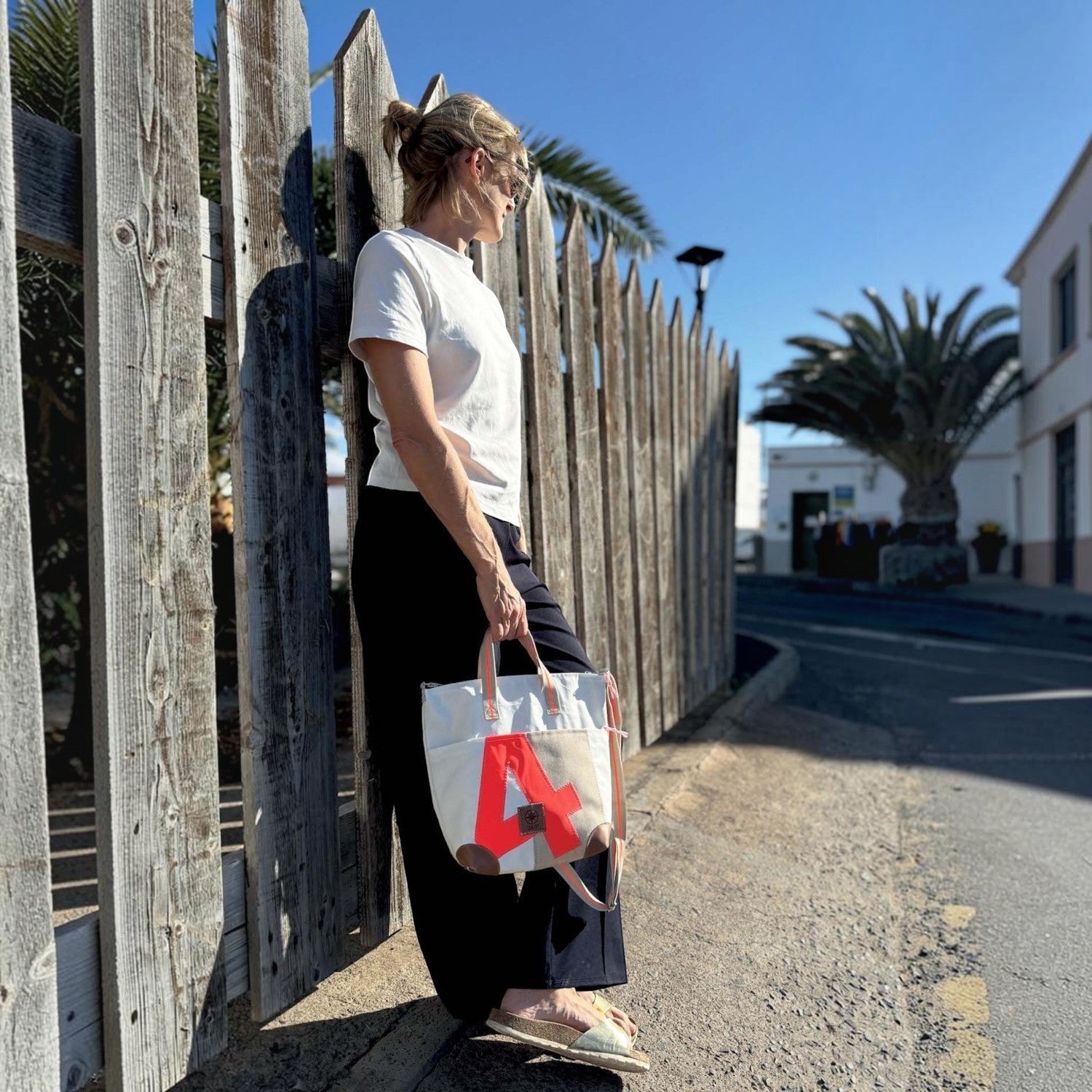 Lieblingstasche Deern Mini canvas tote bag with red letter A detail held by a woman leaning against a wooden fence